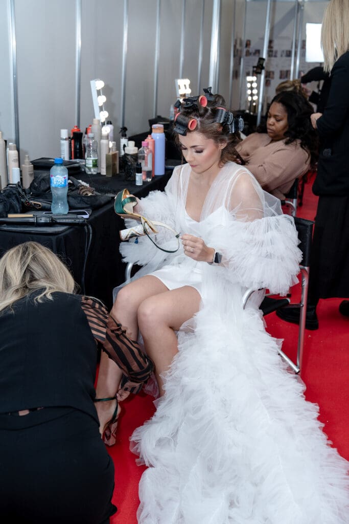 Model getting bridal hair and makeup prepared backstage.